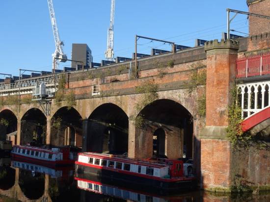 The red brick arches of the 1849 bridge catch the sun as two wide beam cruisers rest alongside
